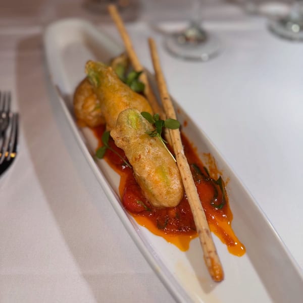 Fried zucchini flowers with tomato sauce and breadsticks on a white rectangular plate at Janina Bistro.