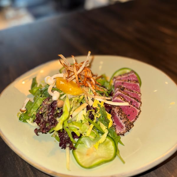 Seared tuna slices with a side salad, topped with crispy fried onions and orange segments.